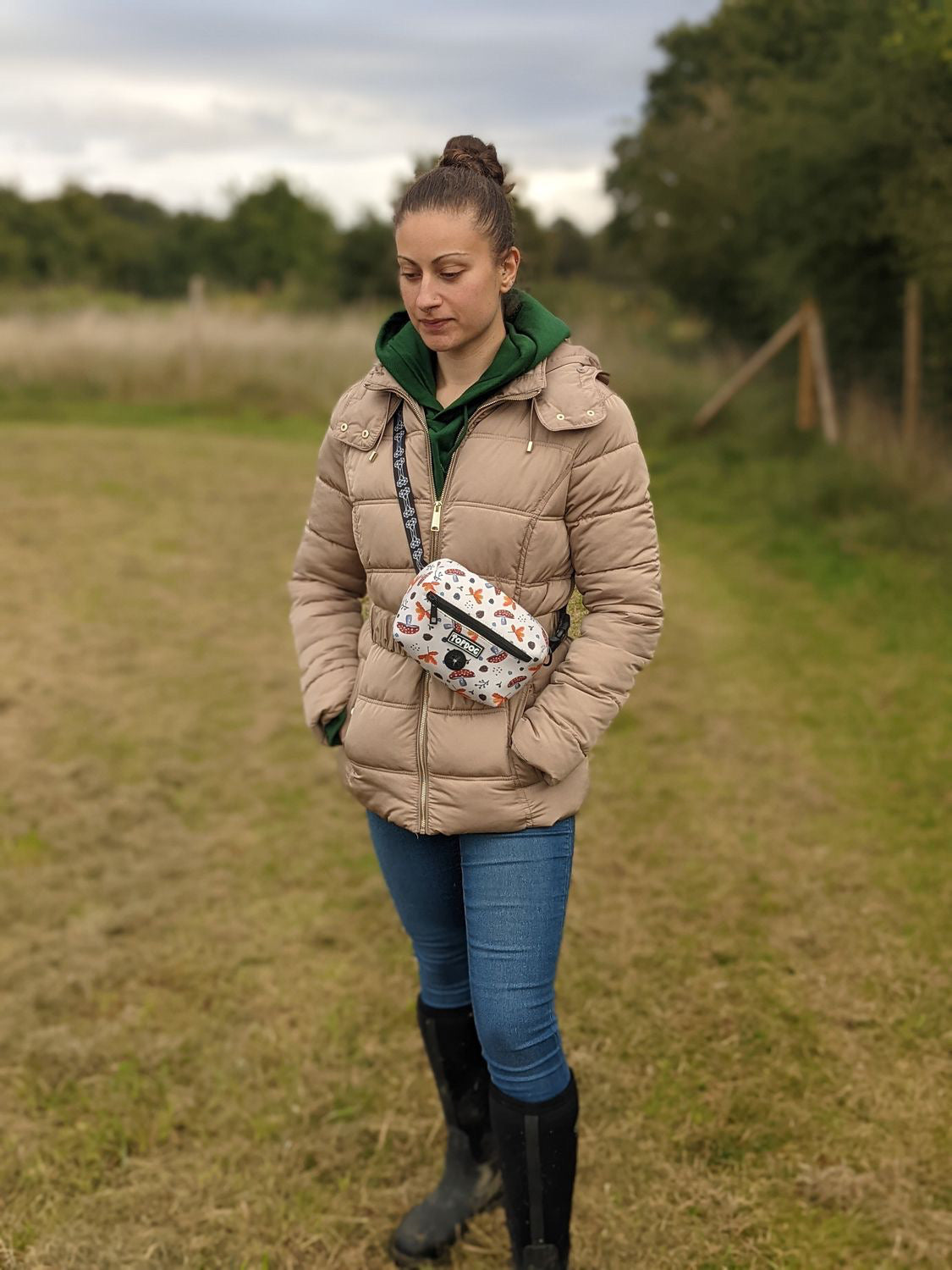 Young woman wearing TopDog Harnesses Matching Essential Dog walking bag standing in a meadow